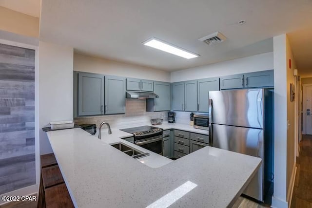 kitchen featuring a kitchen bar, light hardwood / wood-style flooring, kitchen peninsula, and appliances with stainless steel finishes