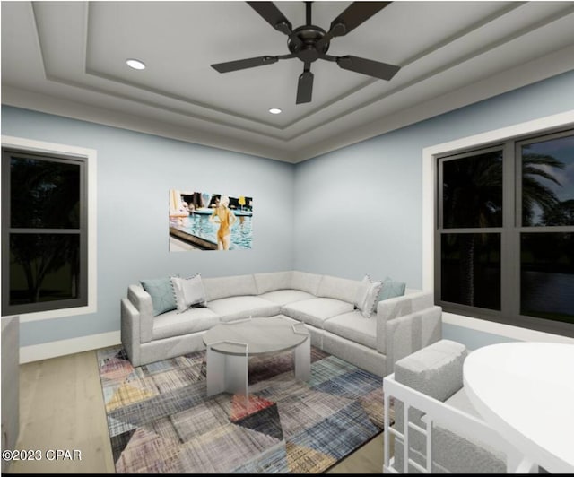 living room with a tray ceiling, ceiling fan, and light hardwood / wood-style flooring