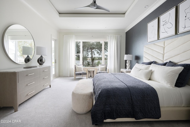 carpeted bedroom with ceiling fan and a tray ceiling