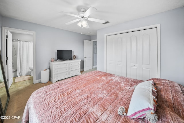 bedroom with a closet, ensuite bathroom, light colored carpet, and ceiling fan