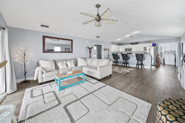 living room featuring lofted ceiling, ceiling fan, dark hardwood / wood-style floors, and washer / dryer