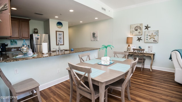 dining area with dark wood-type flooring, sink, and ornamental molding