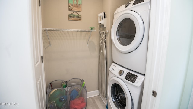 laundry room featuring hardwood / wood-style floors and stacked washer / dryer