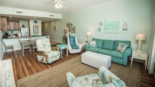 living room with dark wood-type flooring, crown molding, and ceiling fan