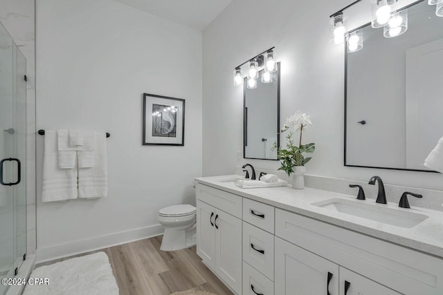 bathroom featuring walk in shower, hardwood / wood-style floors, large vanity, double sink, and toilet