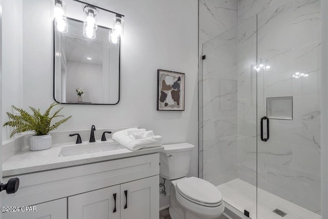 bathroom featuring toilet, large vanity, and a shower with shower door