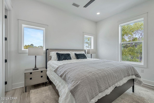 bedroom featuring ceiling fan, light wood-type flooring, and multiple windows