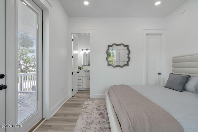 bedroom with sink, light hardwood / wood-style floors, connected bathroom, and access to exterior