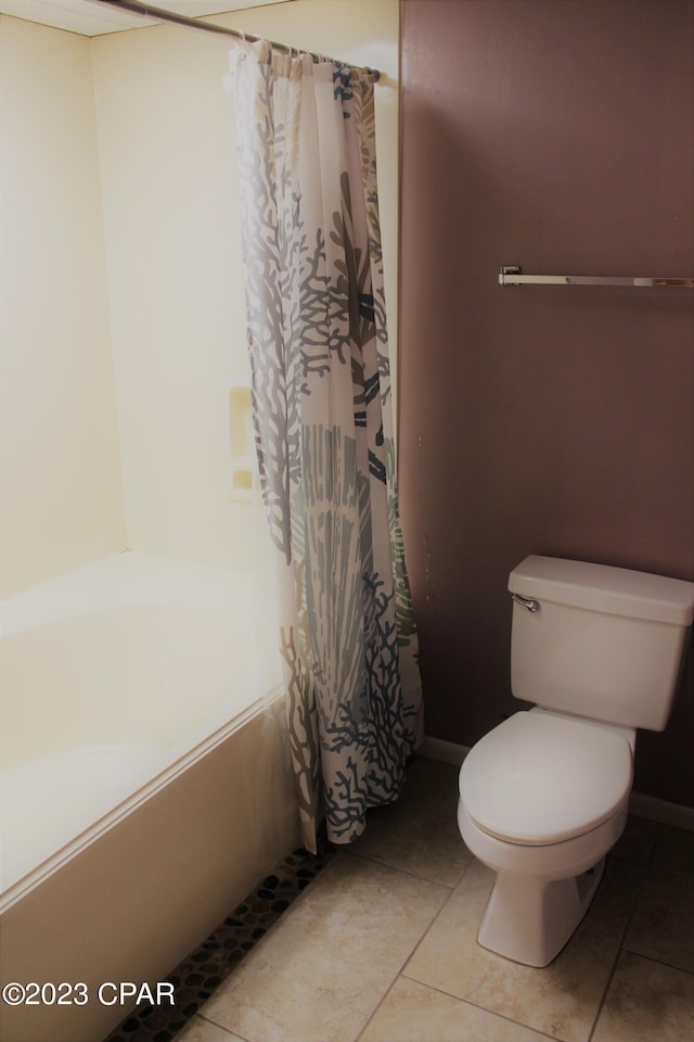 bathroom featuring tile floors, shower / tub combo with curtain, and toilet