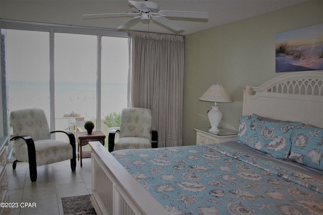 bedroom with light tile floors, ceiling fan, and a water view