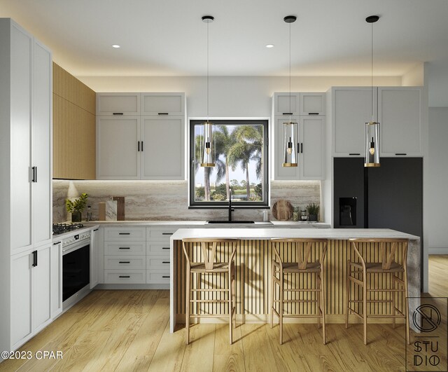 kitchen with oven, pendant lighting, light hardwood / wood-style flooring, and a kitchen bar