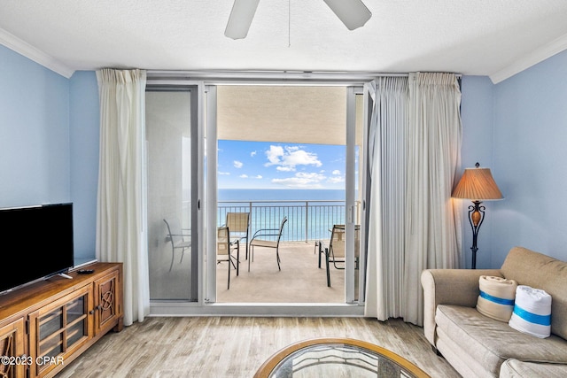 living area featuring a textured ceiling, crown molding, a water view, and wood finished floors