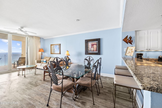 dining area featuring a ceiling fan, wood finished floors, baseboards, and a textured ceiling