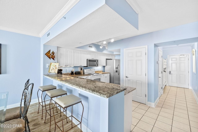 kitchen featuring ornamental molding, white cabinetry, stainless steel appliances, a peninsula, and light tile patterned flooring