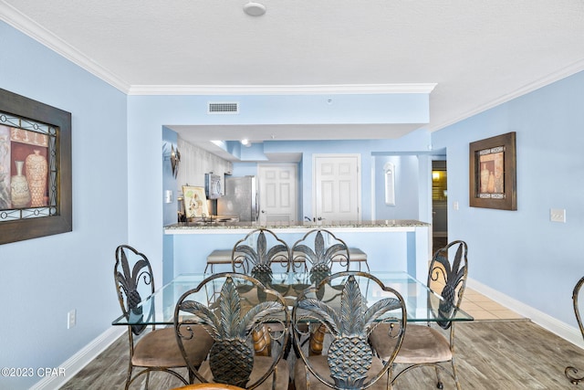 dining space featuring visible vents, crown molding, baseboards, and wood finished floors