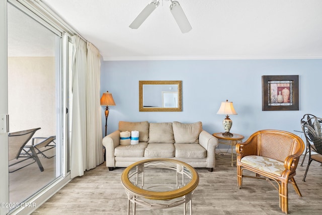 living area with a ceiling fan, crown molding, and light wood-style floors