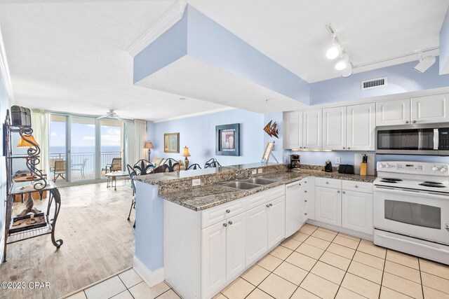 kitchen featuring track lighting, sink, white appliances, and white cabinets