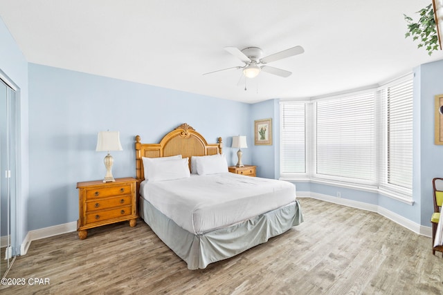 bedroom featuring ceiling fan, a closet, baseboards, and wood finished floors