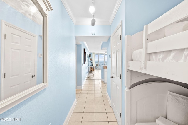 hallway featuring crown molding, light tile patterned flooring, and baseboards