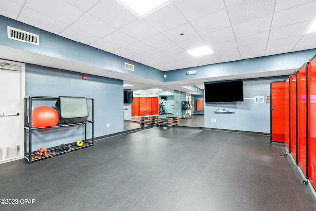 workout area with visible vents, a paneled ceiling, and baseboards