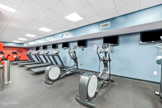 workout area with a paneled ceiling, visible vents, and baseboards