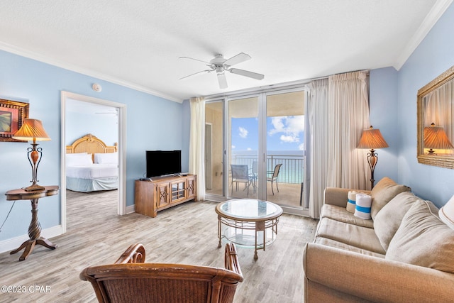 living room featuring a ceiling fan, wood finished floors, baseboards, ornamental molding, and a textured ceiling