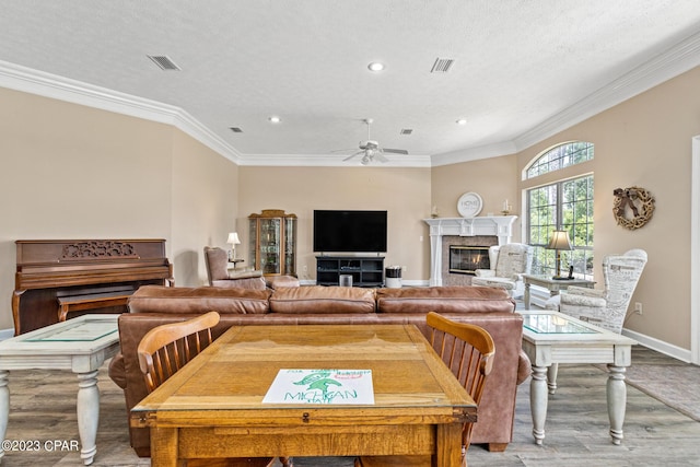 living area featuring visible vents, baseboards, a premium fireplace, light wood-style flooring, and ornamental molding