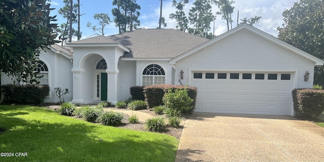 ranch-style home with stucco siding, a shingled roof, concrete driveway, a front yard, and an attached garage