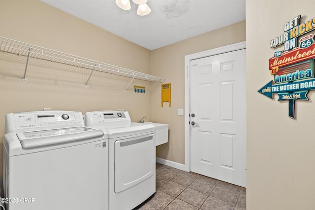 laundry area featuring light tile patterned floors, laundry area, washing machine and dryer, and baseboards