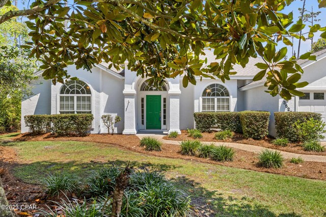 view of front of home with a front lawn, an attached garage, and stucco siding