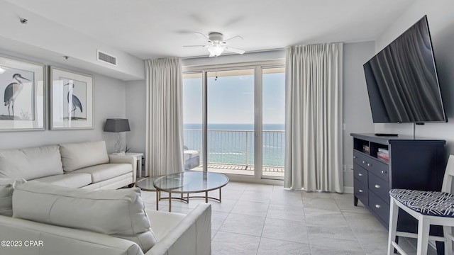 tiled living room featuring a water view, a healthy amount of sunlight, and ceiling fan