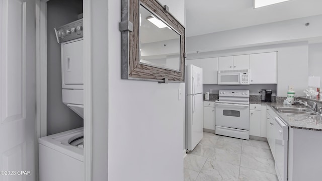 kitchen with light tile floors, stacked washer / dryer, white appliances, white cabinets, and sink