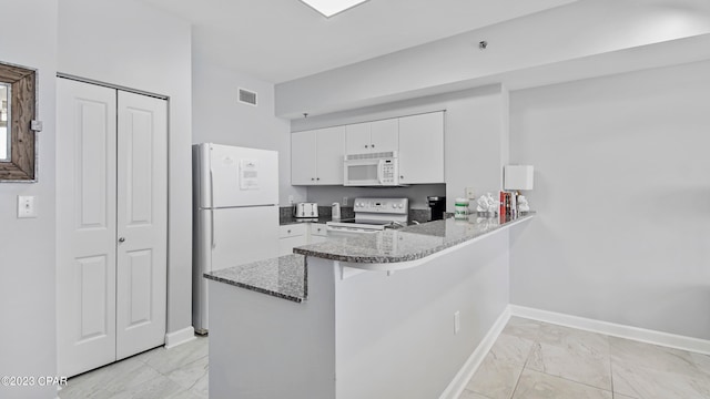 kitchen with kitchen peninsula, white appliances, light tile floors, white cabinets, and light stone counters