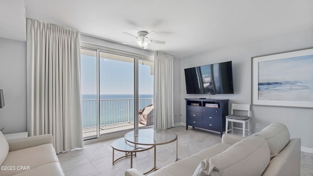 tiled living room featuring ceiling fan and a water view