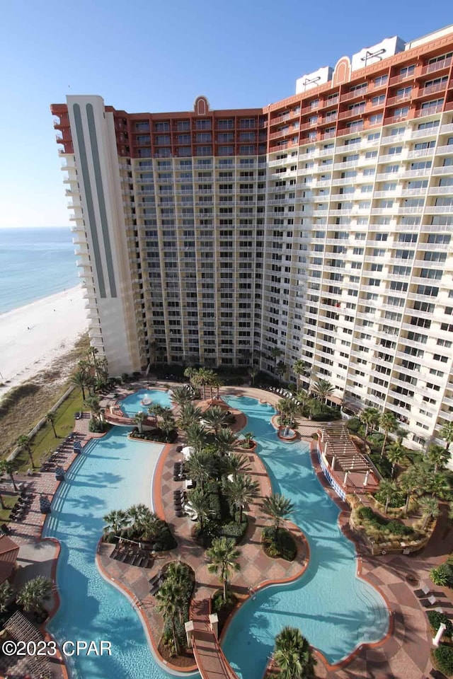 view of property with a water view, a view of the beach, and a community pool