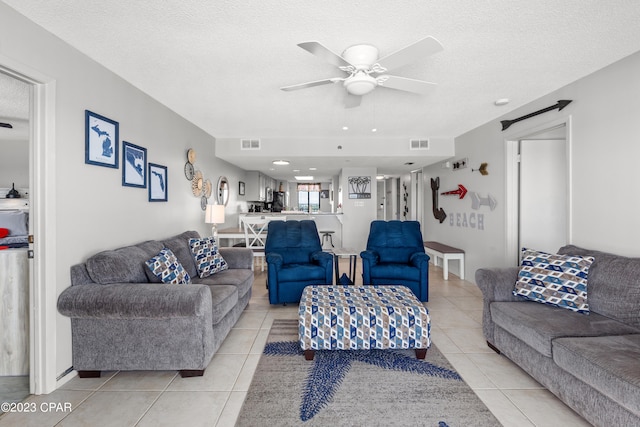 tiled living room with ceiling fan and a textured ceiling