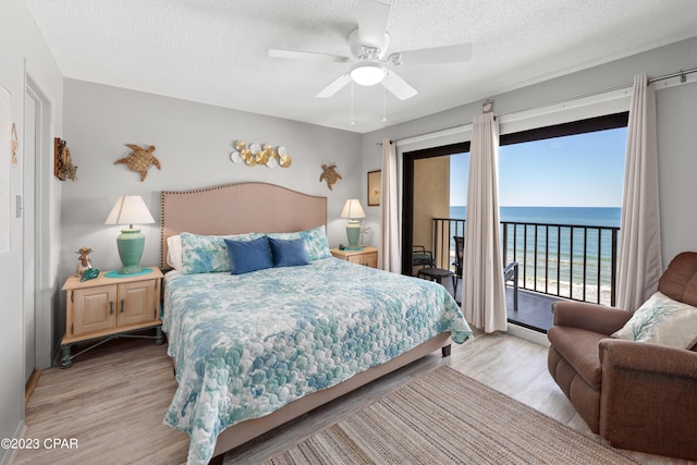 bedroom with access to outside, a water view, ceiling fan, and light hardwood / wood-style flooring