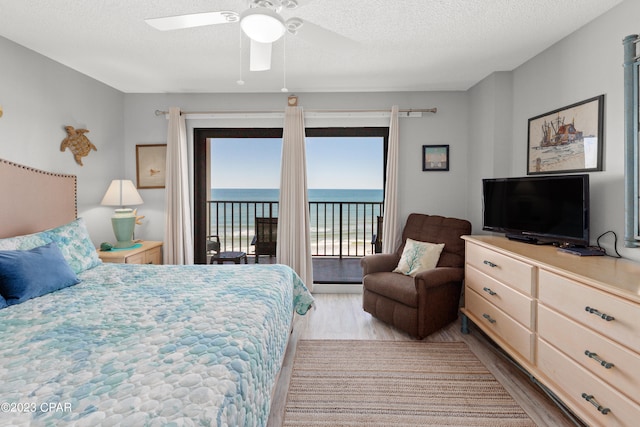 bedroom featuring access to outside, a textured ceiling, light wood-type flooring, and ceiling fan