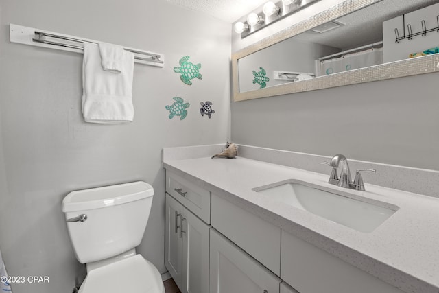 bathroom with vanity, toilet, and a textured ceiling