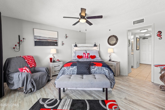 bedroom featuring ceiling fan, a textured ceiling, and light wood-type flooring