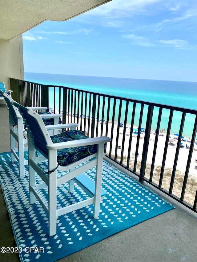 balcony with a water view and a view of the beach