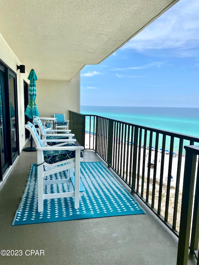 balcony featuring a water view and a beach view