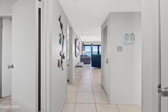 corridor featuring a textured ceiling and light tile patterned floors