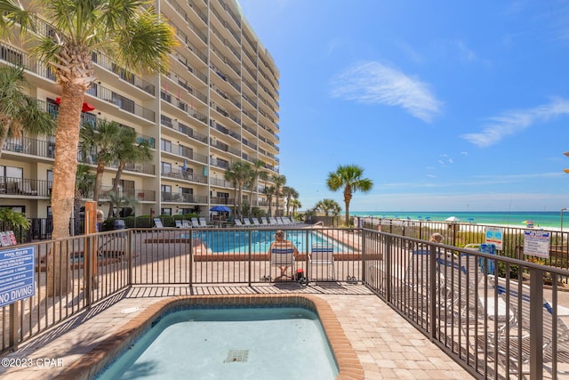 view of pool with a water view and a beach view