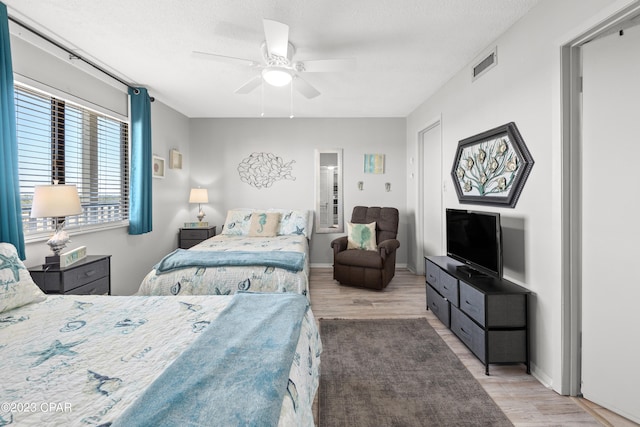 bedroom with light hardwood / wood-style floors, ceiling fan, and a textured ceiling