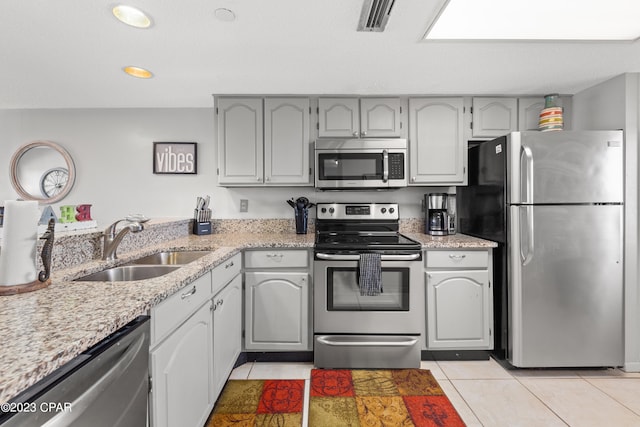 kitchen with light tile patterned floors, gray cabinets, appliances with stainless steel finishes, and sink