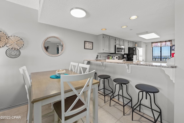 dining space with a textured ceiling and light tile patterned flooring