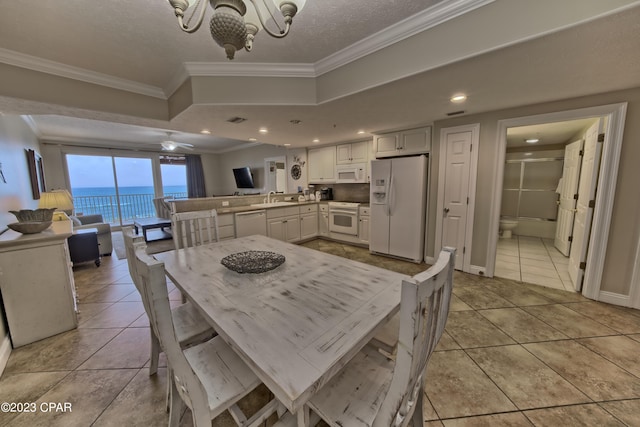 tiled dining room with a textured ceiling, ceiling fan, crown molding, and sink