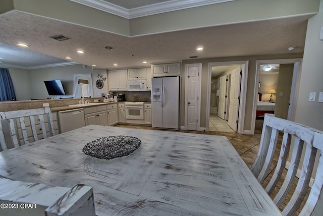 dining space featuring crown molding, light tile patterned flooring, sink, and a textured ceiling