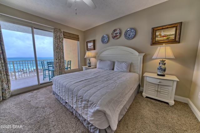 carpeted bedroom with access to exterior, a textured ceiling, a water view, and ceiling fan